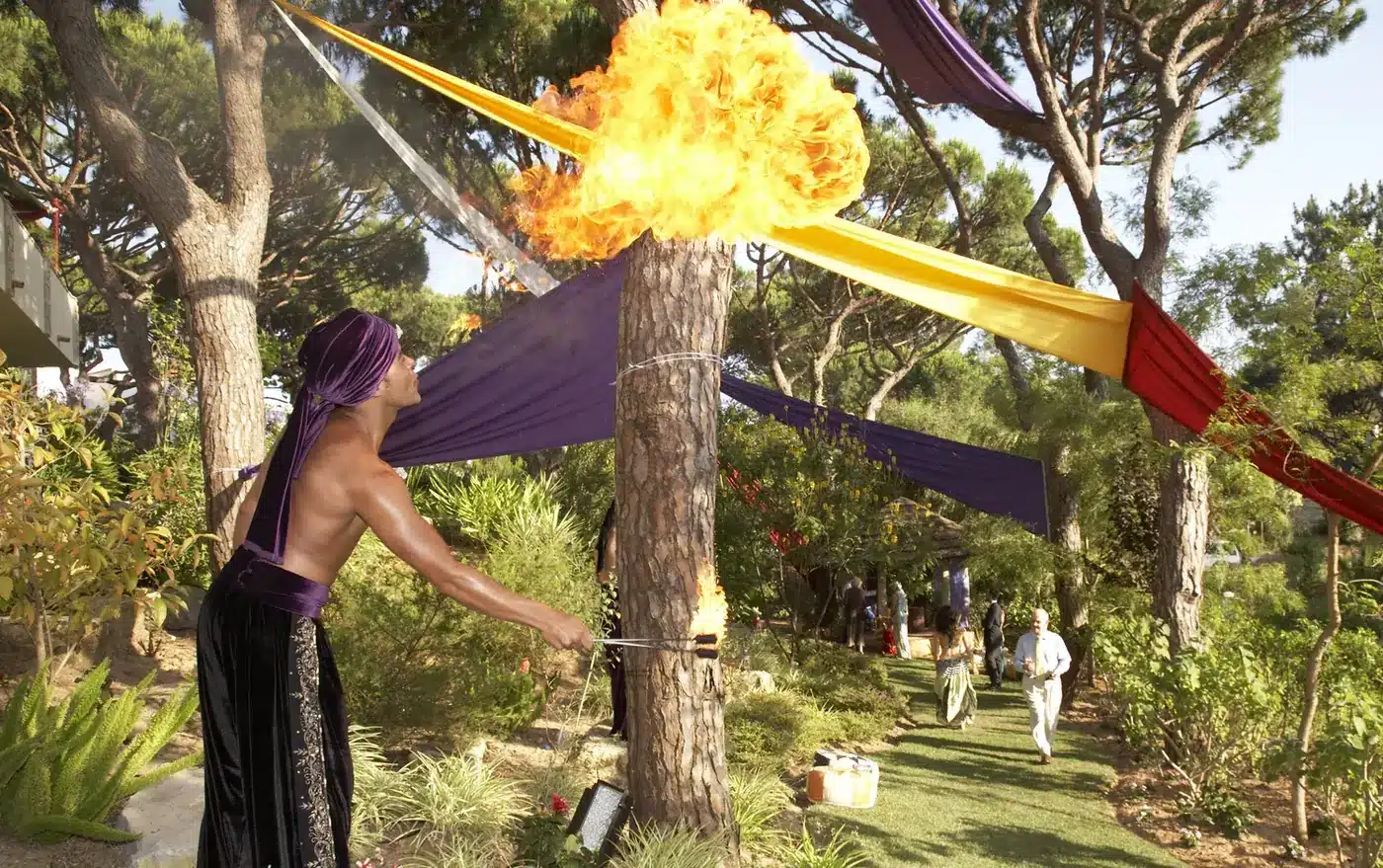 Fire performer at the entrance to a Moroccan themed garden event as guests walk up the path toward the arrival point