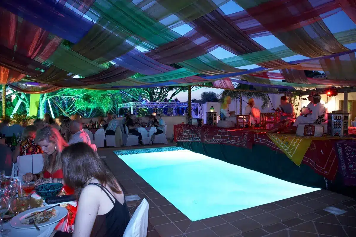 Draped canopy and an illuminated pool drawing guest attention at an evening event, an example of visual hierarchy in a physical space